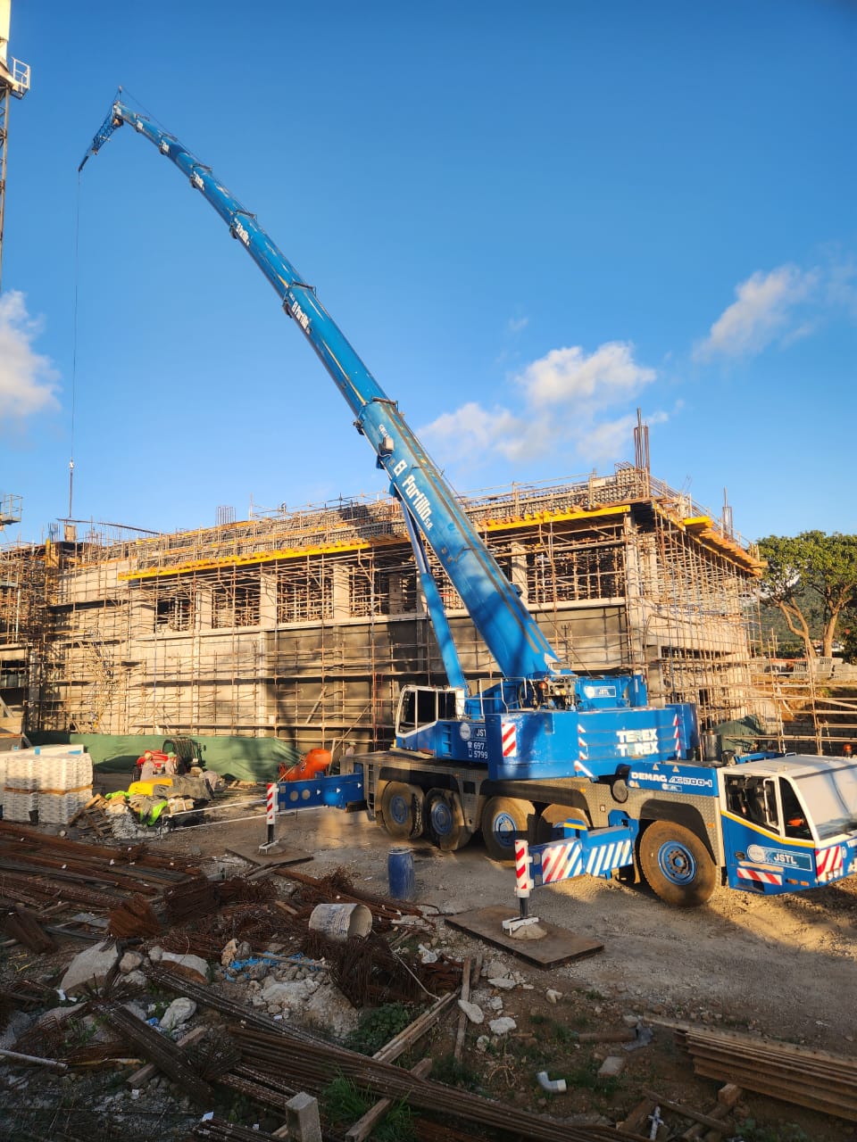 JSTL blue Demag crane at a scaffolded building