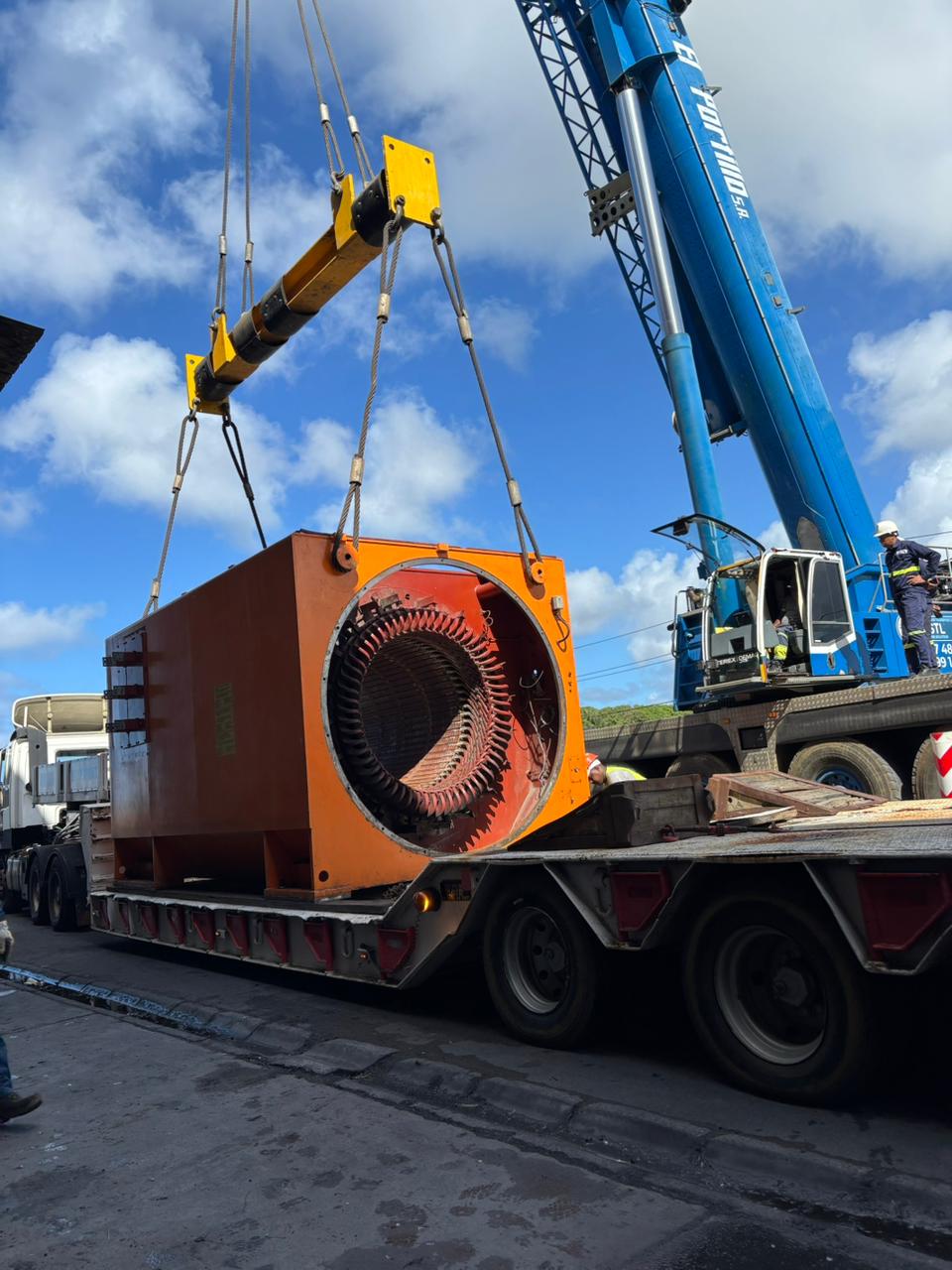 JSTL crane lifting an orange generator stator on a low-bed