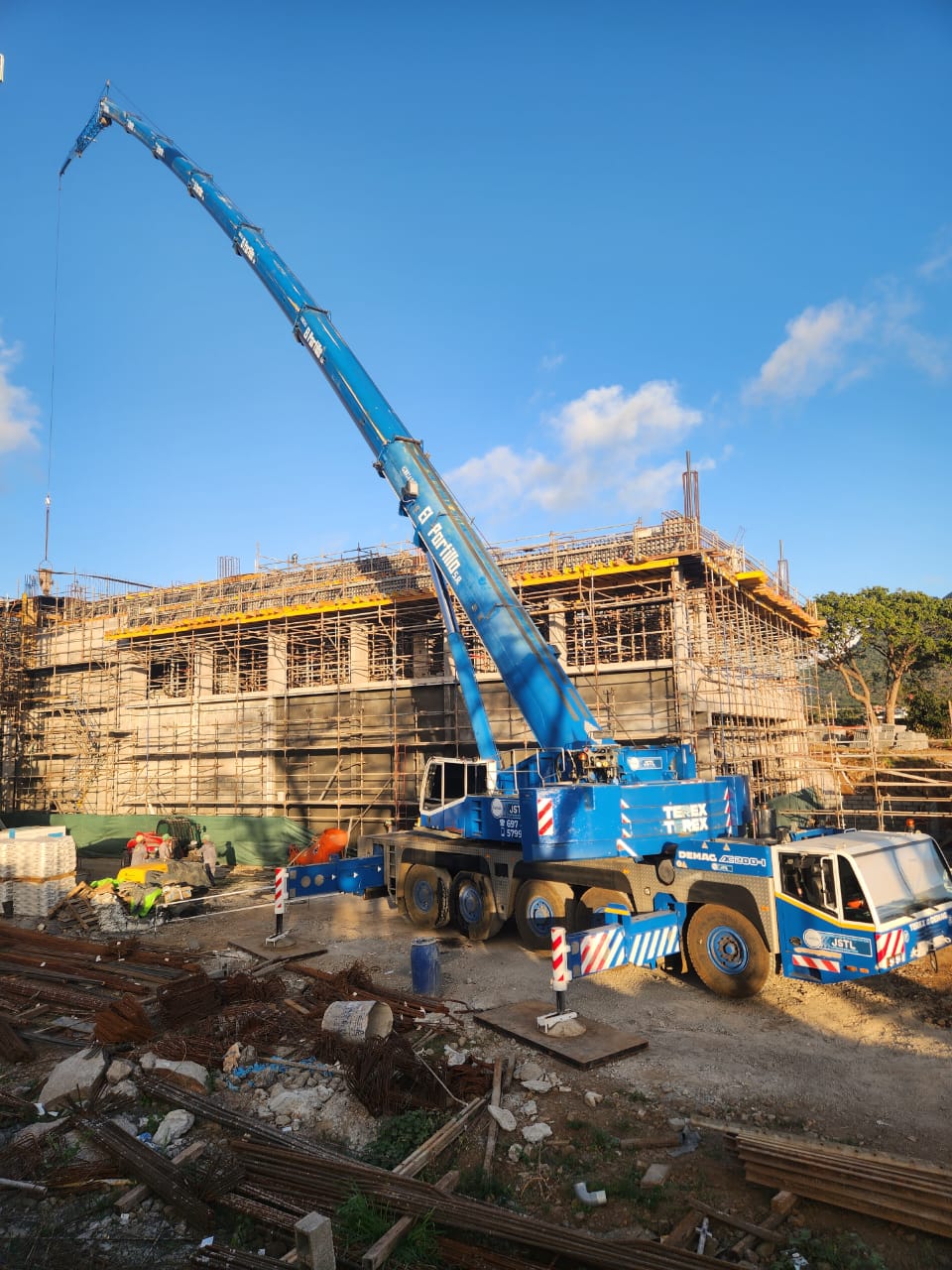 Blue Demag boom extended over a building under construction