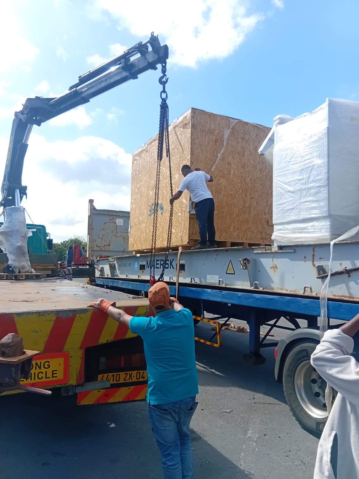 Truck crane loading a crate onto a Maersk flatbed